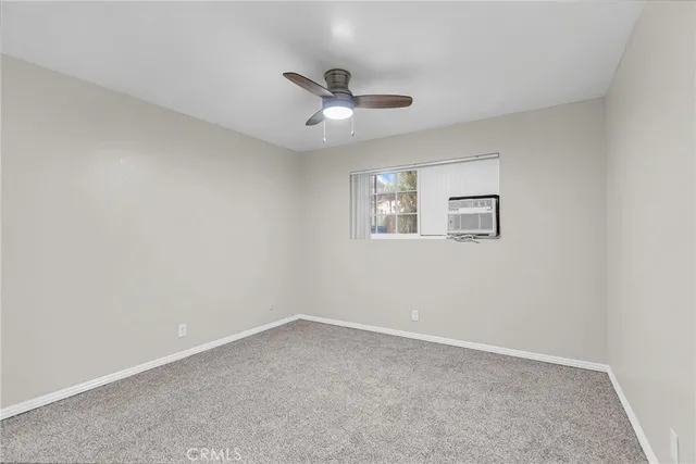 an empty room with a window and ceiling fan