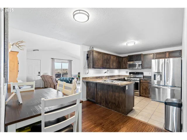 a kitchen with stainless steel appliances kitchen island granite countertop a stove refrigerator and cabinets