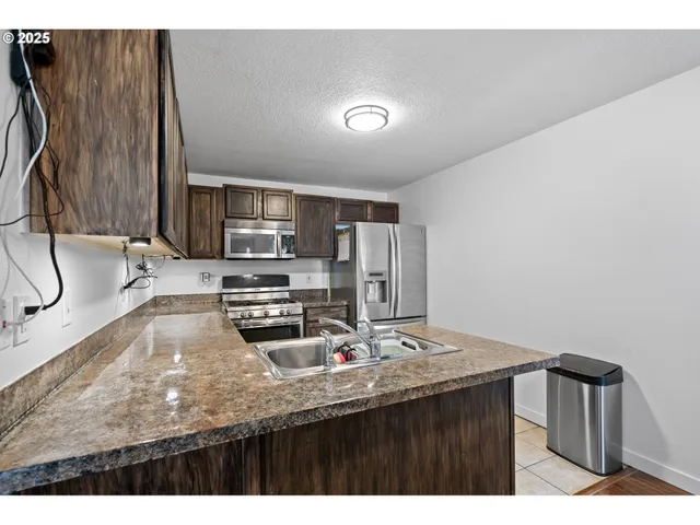 a kitchen with stainless steel appliances granite countertop a sink refrigerator and cabinets