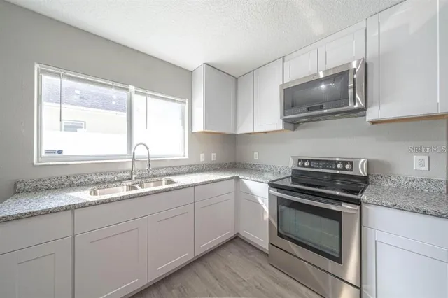 a kitchen with granite countertop a sink and steel appliances