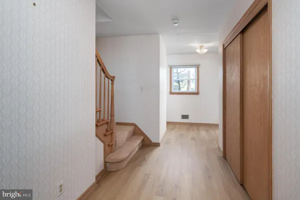a view of a hallway with wooden floor and closet