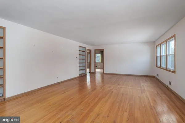 a view of empty room with wooden floor and window