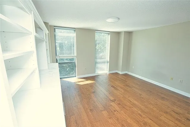a view of an empty room with wooden floor and a window