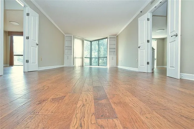a view of an empty room with wooden floor and a window