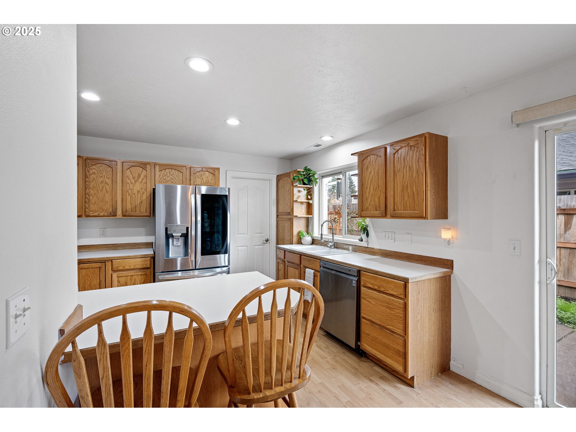 3785 Dove Lane Eugene, OR 97402 - Photo 17 of 43 a kitchen with stainless steel appliances granite countertop a sink a stove a refrigerator a microwave a dining table and chairs with wooden floor