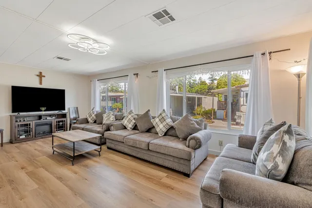 a living room with furniture a flat screen tv and a large window