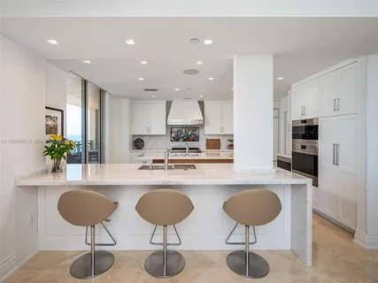 a kitchen with stainless steel appliances granite countertop a kitchen island a stove a cabinets and chairs