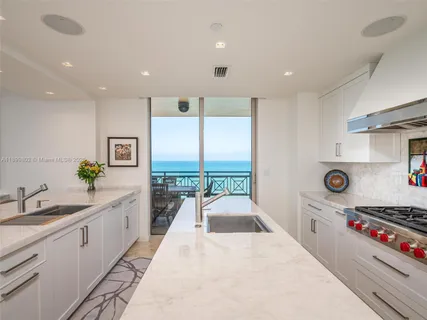 a large white kitchen with stainless steel appliances granite countertop a lot of counter space and a sink