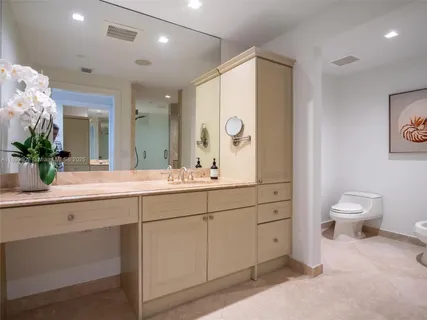 a bathroom with a sink a toilet and a large mirror
