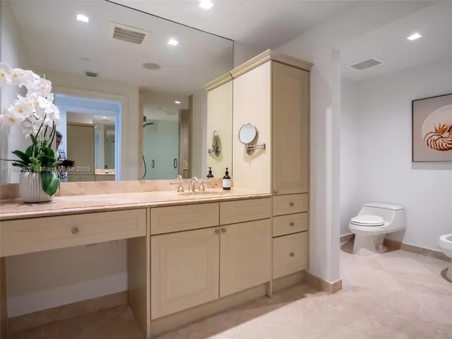 a bathroom with a sink a toilet and a large mirror