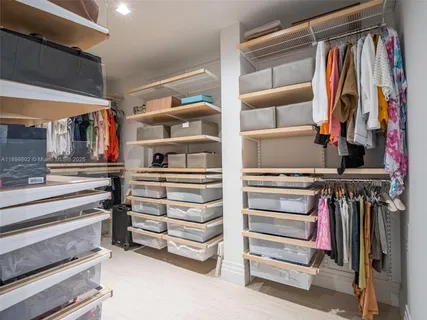 a view of walk in closet with clothes and shoes