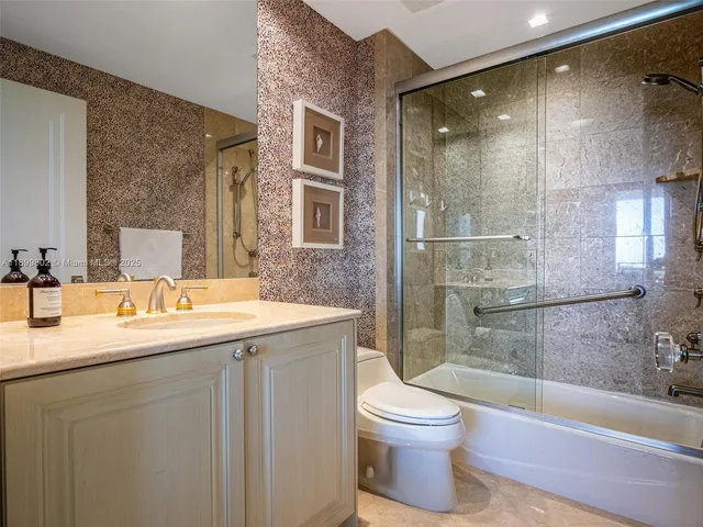a bathroom with a granite countertop sink toilet and shower