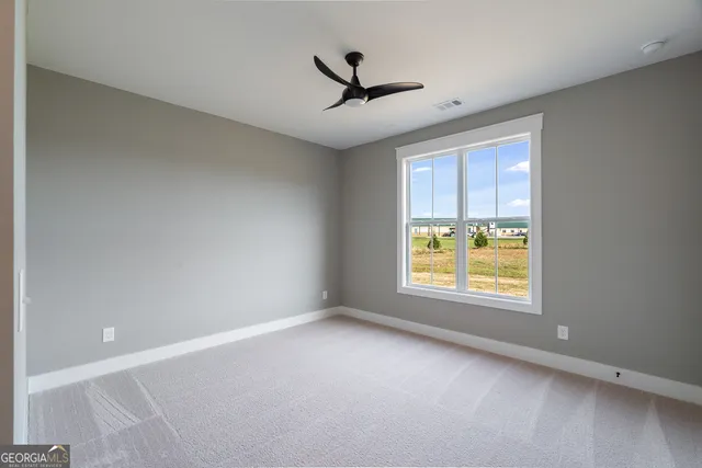 an empty room with windows and ceiling fan