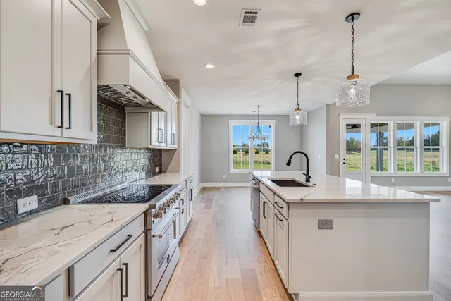 a kitchen with stainless steel appliances granite countertop a sink a stove and a wooden floors