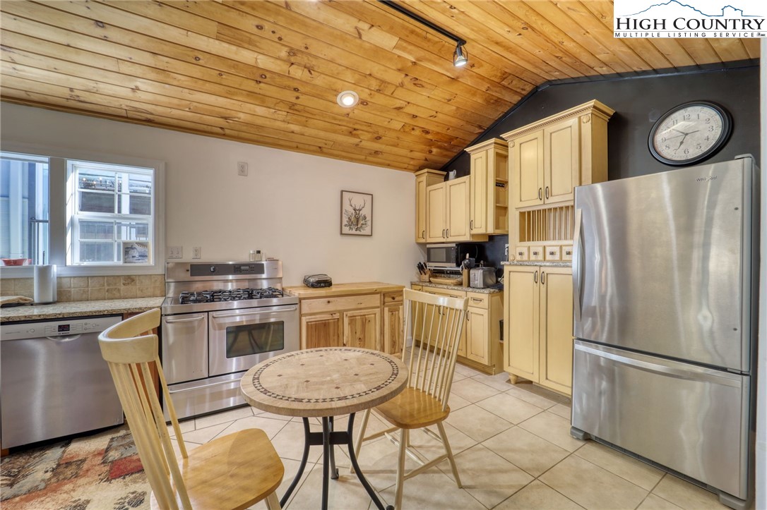 72 Arnett Road Banner Elk, NC 28604 - Photo 5 of 38 a kitchen with stainless steel appliances granite countertop a stove a refrigerator a sink a dining table and chairs with wooden floor