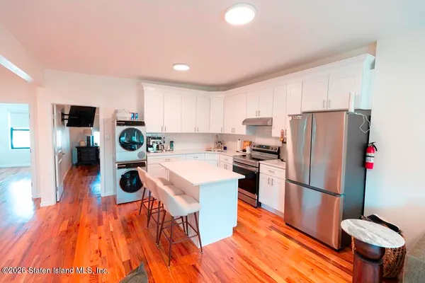 a kitchen with stainless steel appliances granite countertop a refrigerator a stove top oven a sink dishwasher and white cabinets with wooden floor