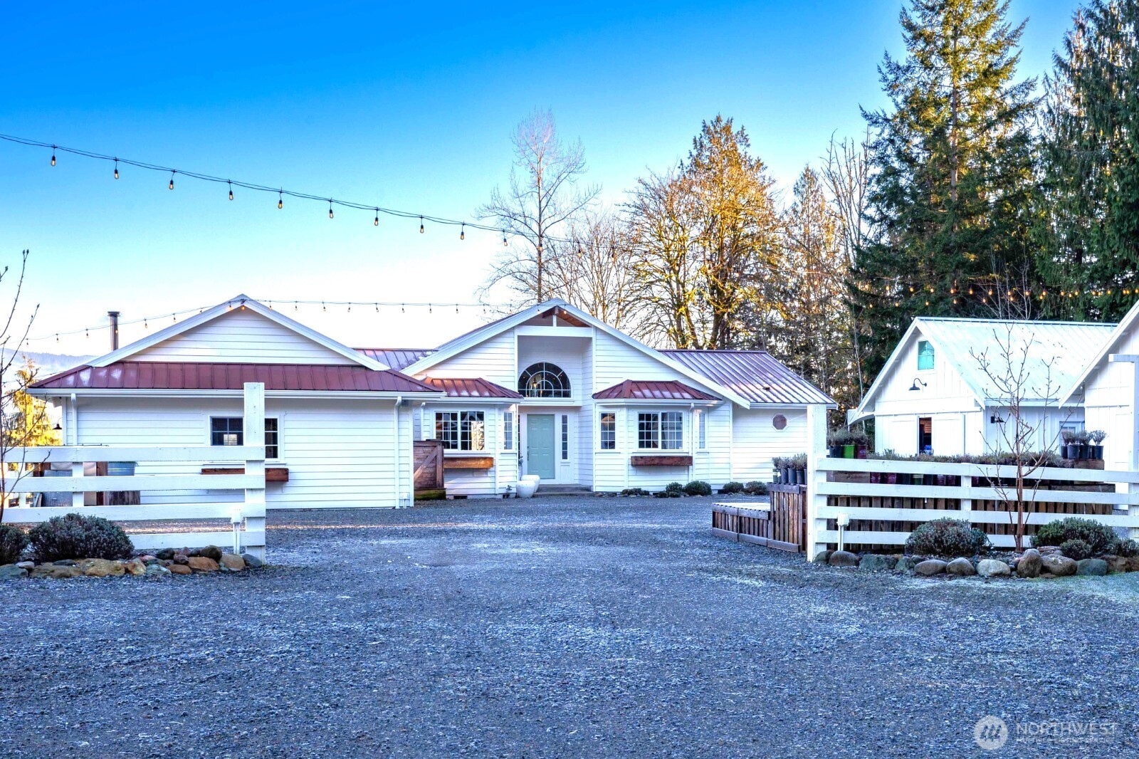 a view of a white house with a big yard and large trees
