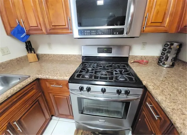 a kitchen with stainless steel appliances granite countertop a stove a sink and a microwave