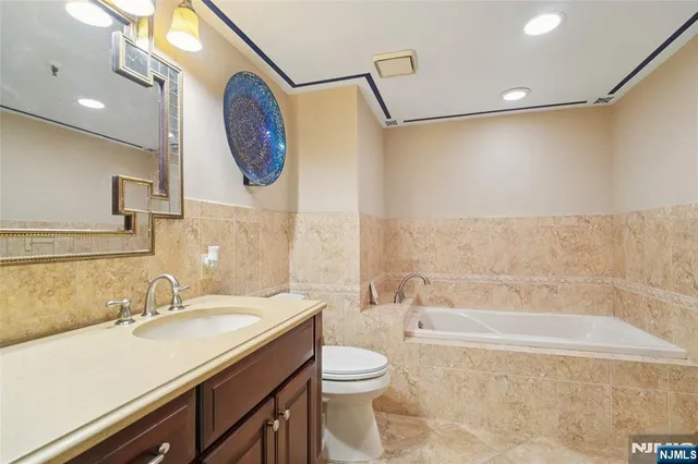 a bathroom with a granite countertop sink mirror vanity and toilet