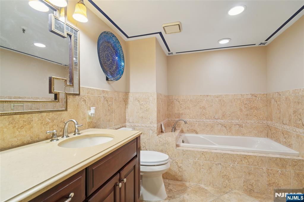 245 Prospect Avenue, Unit 5B Hackensack, NJ 07601 - Photo 17 of 35 a bathroom with a granite countertop sink mirror vanity and toilet