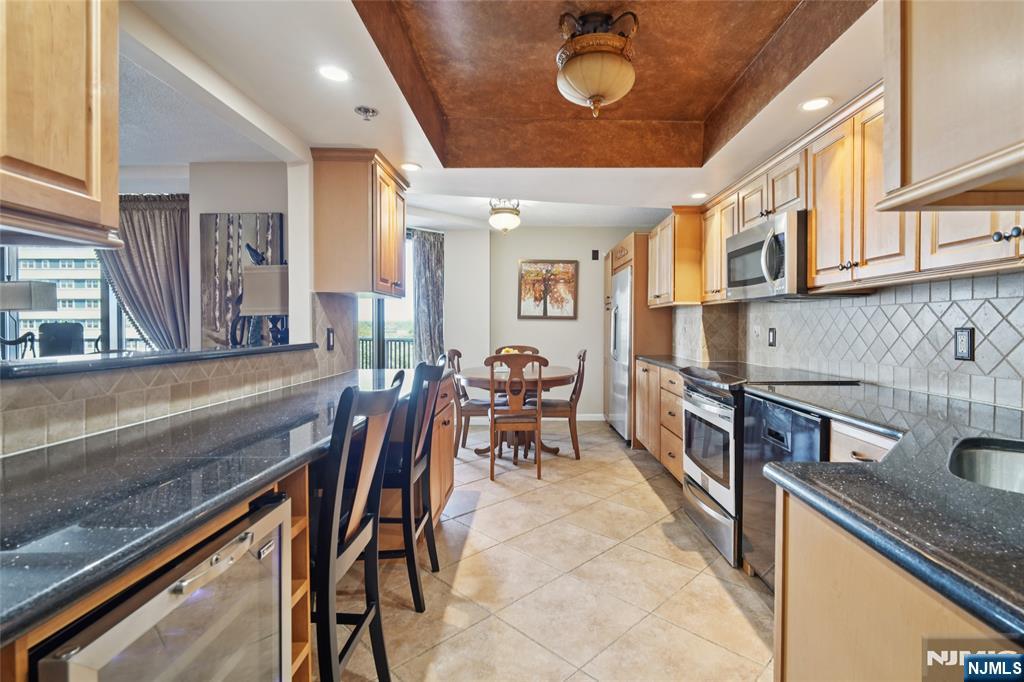 245 Prospect Avenue, Unit 5B Hackensack, NJ 07601 - Photo 10 of 35 a open kitchen with stainless steel appliances granite countertop a stove a sink a dining table and chairs with wooden floor