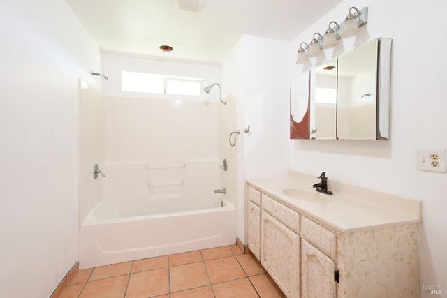 a bathroom with a bathtub a sink a vanity and a mirror