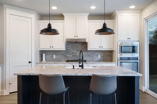 a kitchen with stainless steel appliances granite countertop a sink a stove and a refrigerator