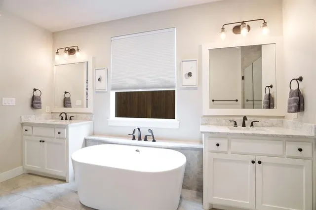 a bathroom with a double vanity sink mirror and bathtub