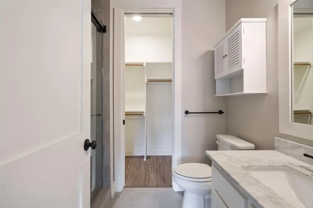 a bathroom with a granite countertop toilet and a sink