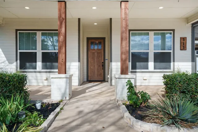 a front view of a house with a large window and potted plants