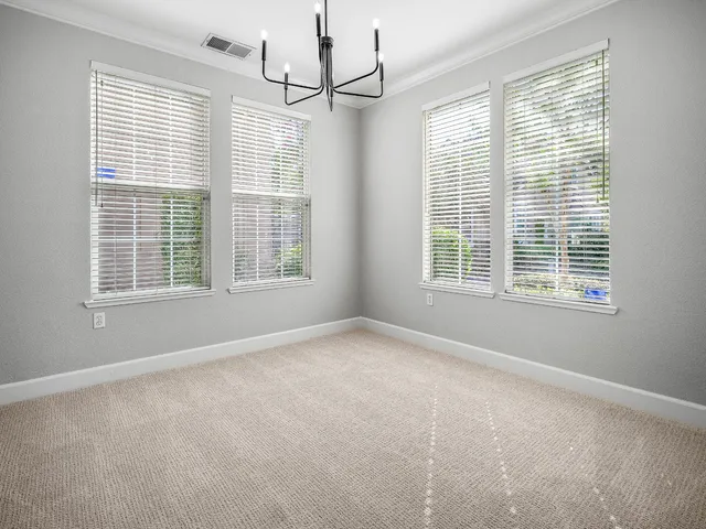 a view of an empty room with a window and chandelier fan