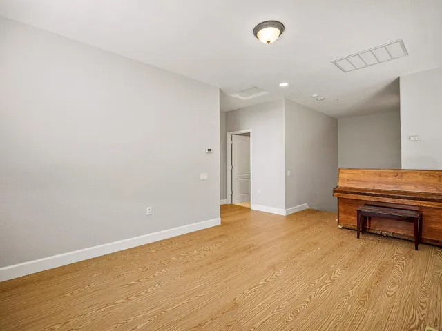 a view of a room with a piano and wooden floor