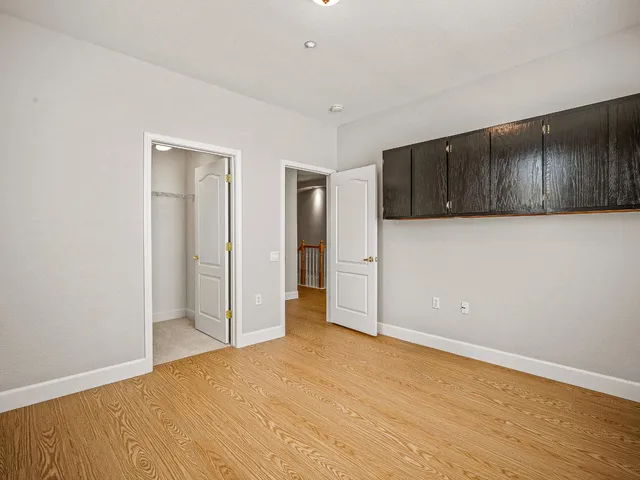 a view of an empty room with wooden floor and cabinet
