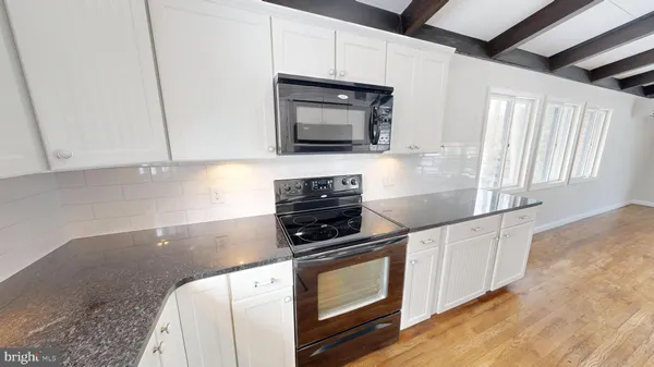 a kitchen with granite countertop a stove and a microwave with cabinets
