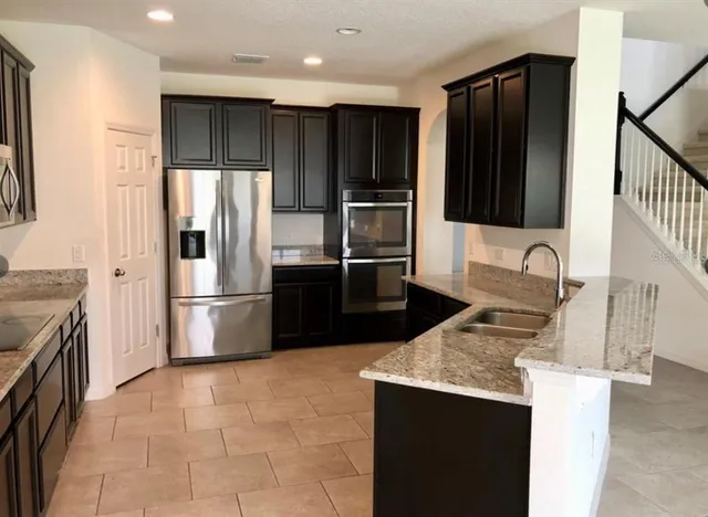 a kitchen with stainless steel appliances granite countertop a refrigerator a stove and a sink