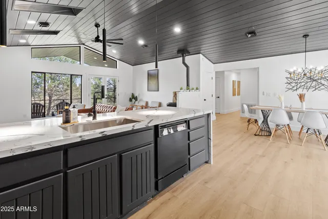 a kitchen with a sink stainless steel appliances wooden floor and view living room