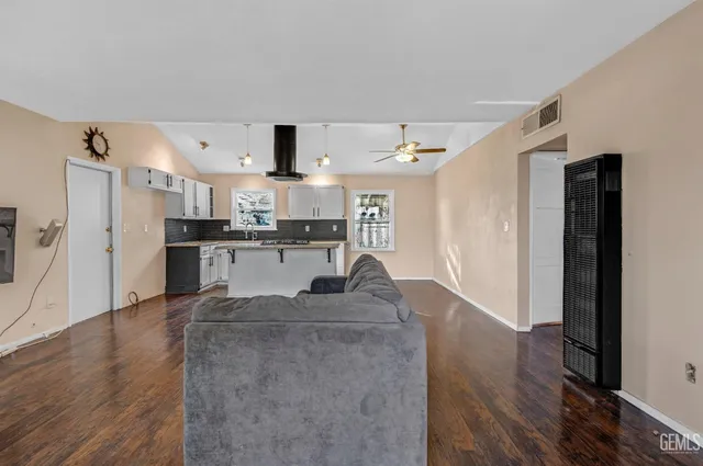 a living room with stainless steel appliances granite countertop furniture and a refrigerator