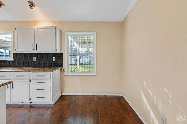 an empty room with wooden floor cabinet and a window