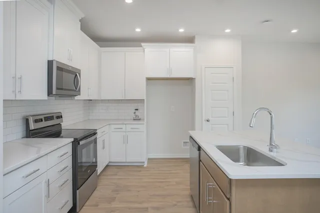 a kitchen with a sink white cabinets and stainless steel appliances