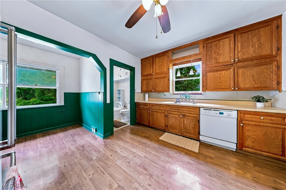 24958 Kennedy Ridge Road North Olmsted, OH 44070 - Photo 12 of 43 Wood-finish flooring, wood cabinetry, white dishwasher, ceiling fan with integrated lighting, and a window above the sink