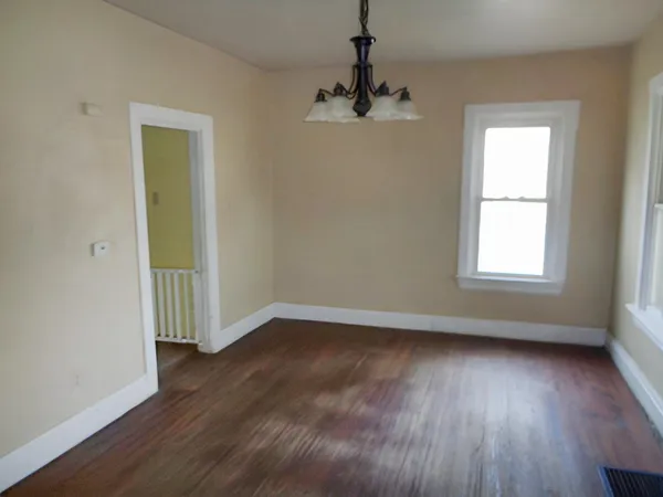 a view of an empty room with a window and wooden floor