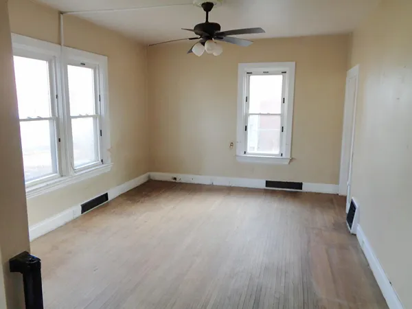 an empty room with windows and fan