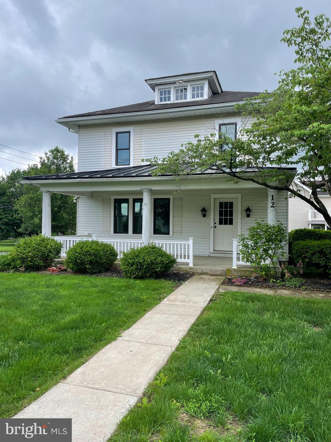 a front view of a house with a yard and potted plants