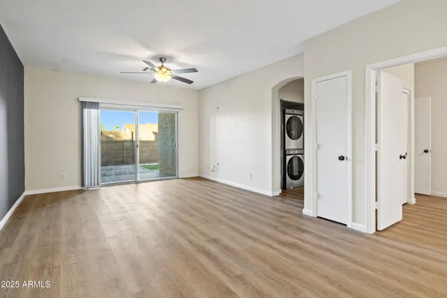 an empty room with wooden floor chandelier fan and windows