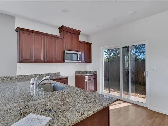 a kitchen with stainless steel appliances granite countertop a stove a sink and a microwave