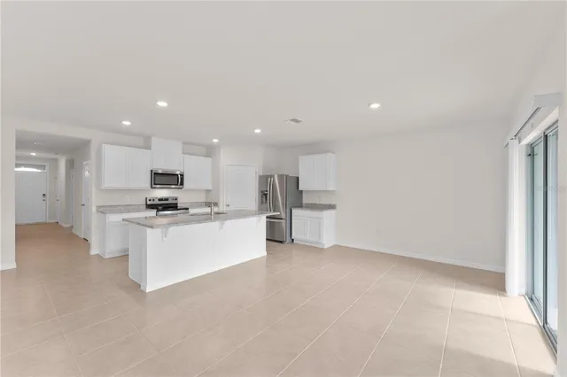 a view of kitchen with kitchen island a sink a stove and a refrigerator with wooden floor