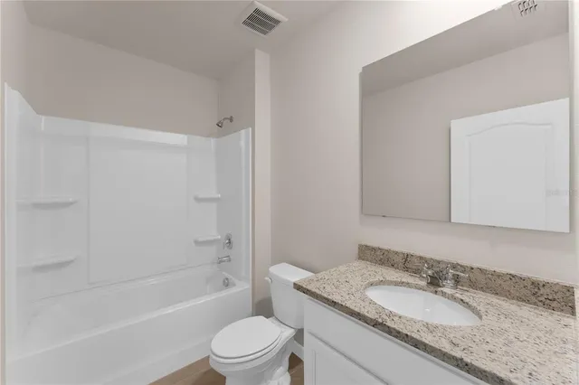 a bathroom with a granite countertop sink toilet mirror and shower