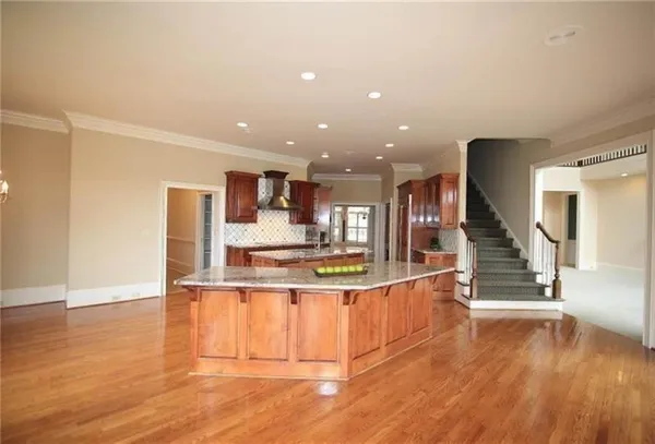 a view of a kitchen with kitchen island wooden floor and stainless steel appliances