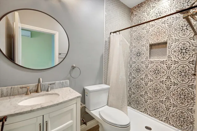 a bathroom with a granite countertop toilet sink mirror and vanity