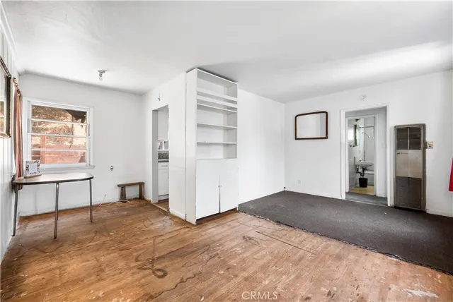 a view of an empty room with window and wooden floor